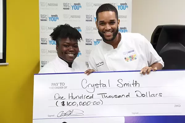 Corporate Chef for Nestle Jamaica and Lead for the TOCUTA Program, Andrew Slolely presenting Krystal Smith with her bursary cheque of $100,000